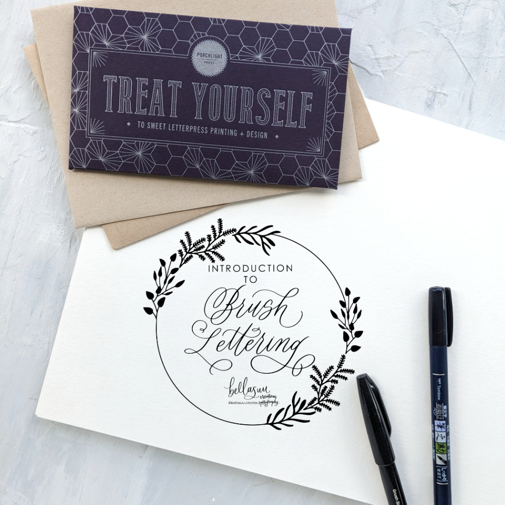 Letterpress printed card with brush lettering and an envelope on a textured surface.